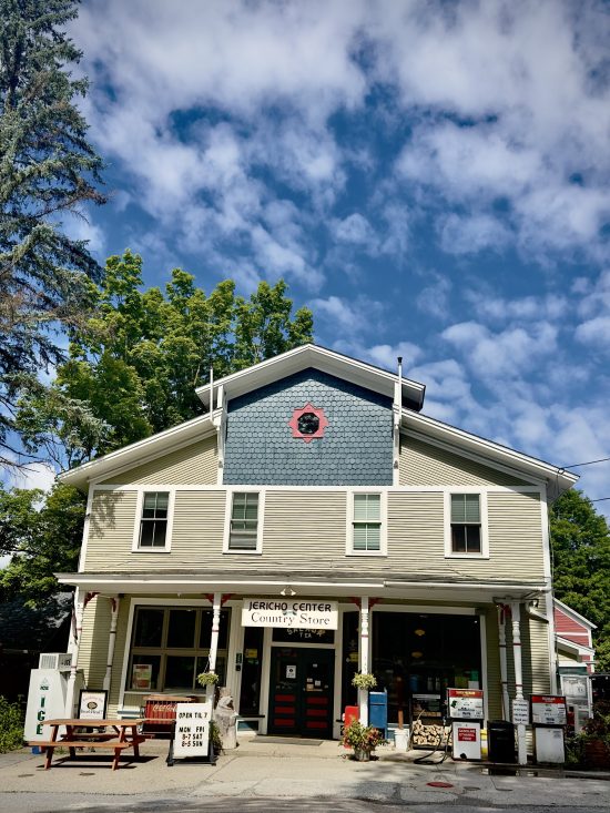 Vermont Country store on a blue sky day with picnic table, ice machine and old fashioned gas pumps outside